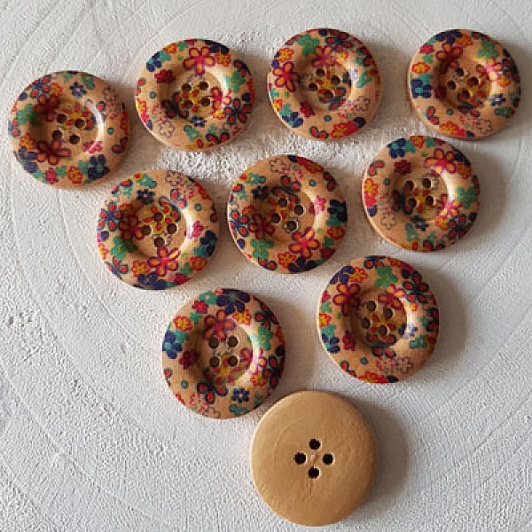 Dix boutons en bois ronds avec motifs de fleurs colorées.