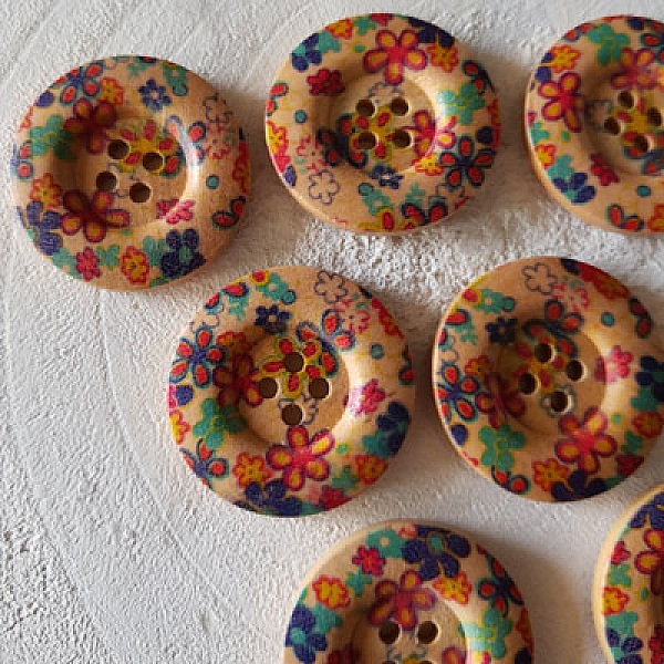Boutons en bois ronds avec motifs de fleurs colorées.