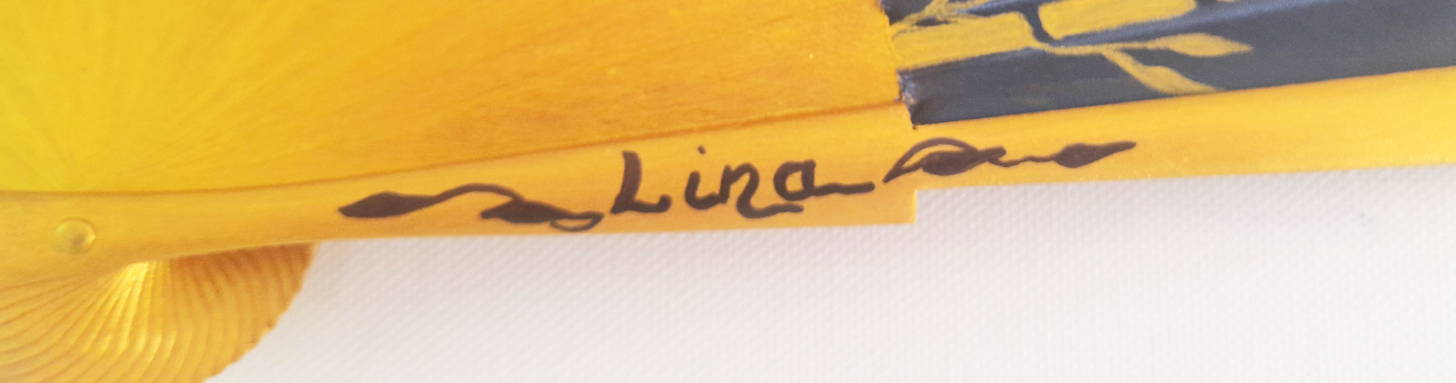 Signature artisanale Nana gravée sur une branche d'éventail en bois.