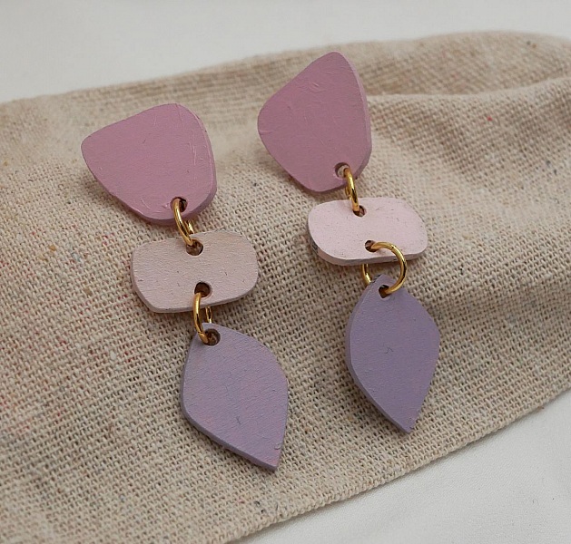 Boucles d'oreilles pendantes en bois aux formes géométriques pastel.