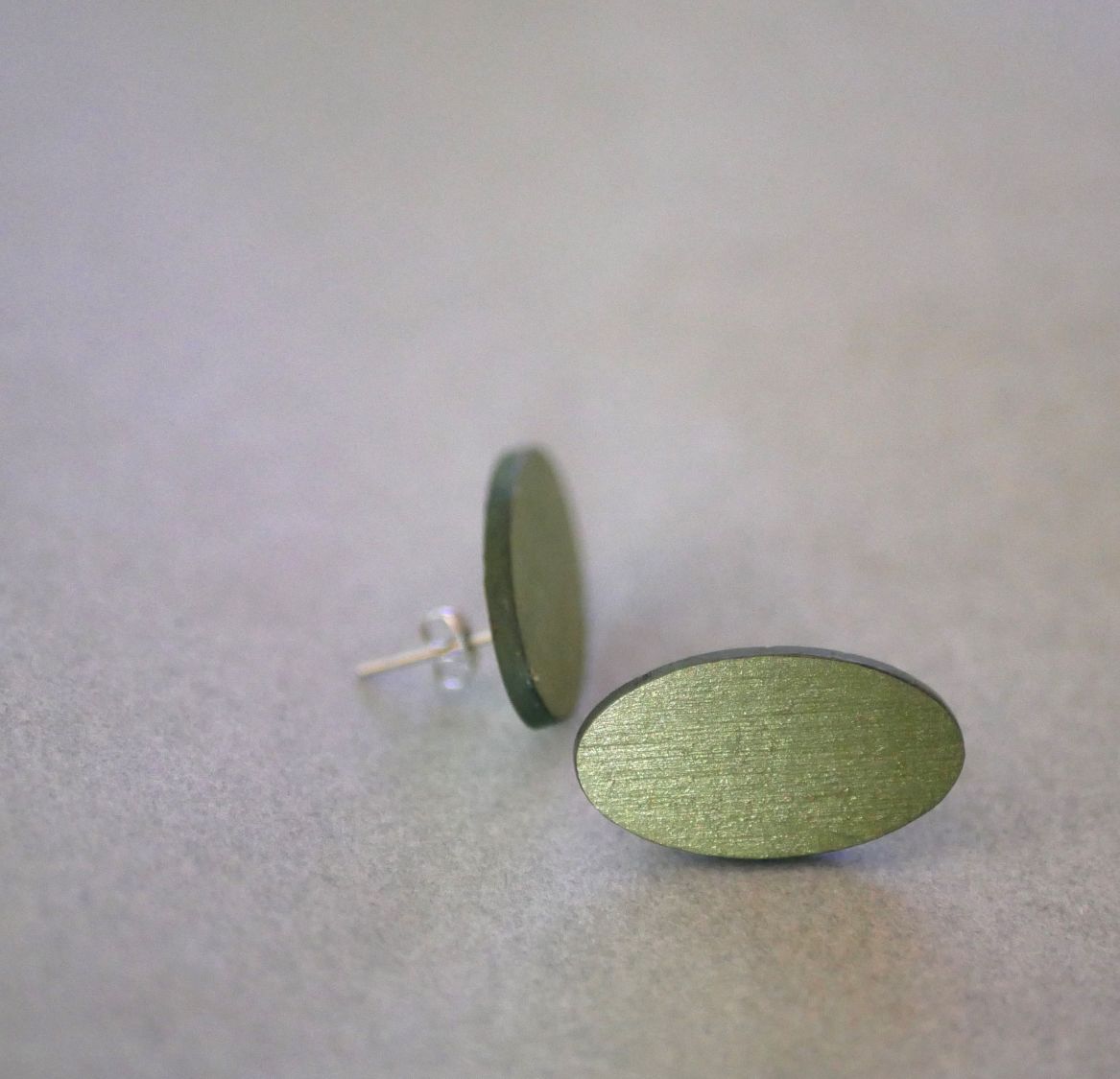 Ovale øredobber i tre malt i en duo av greener med metallisk effekt