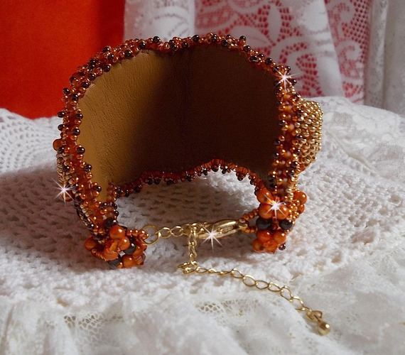 Dame i oransje mansjettarmbånd Haute-Couture brodert med Swarovski-krystaller og Miyuki frøperler.
