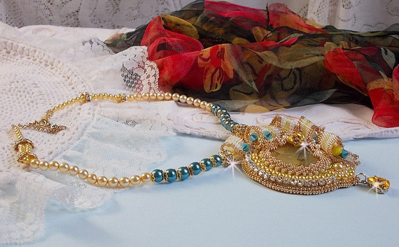 Haute-Couture Sunflower Gold anheng brodert med 24 karat gullbelagte frøperler, en Madagaskar opal og Swarovski krystaller.