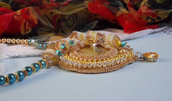 Haute-Couture Sunflower Gold anheng brodert med 24 karat gullbelagte frøperler, en Madagaskar opal og Swarovski krystaller.