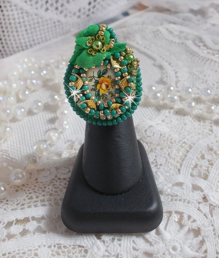 Vakker smaragdring med en keramisk cabochon laget av en gul og grønn rose