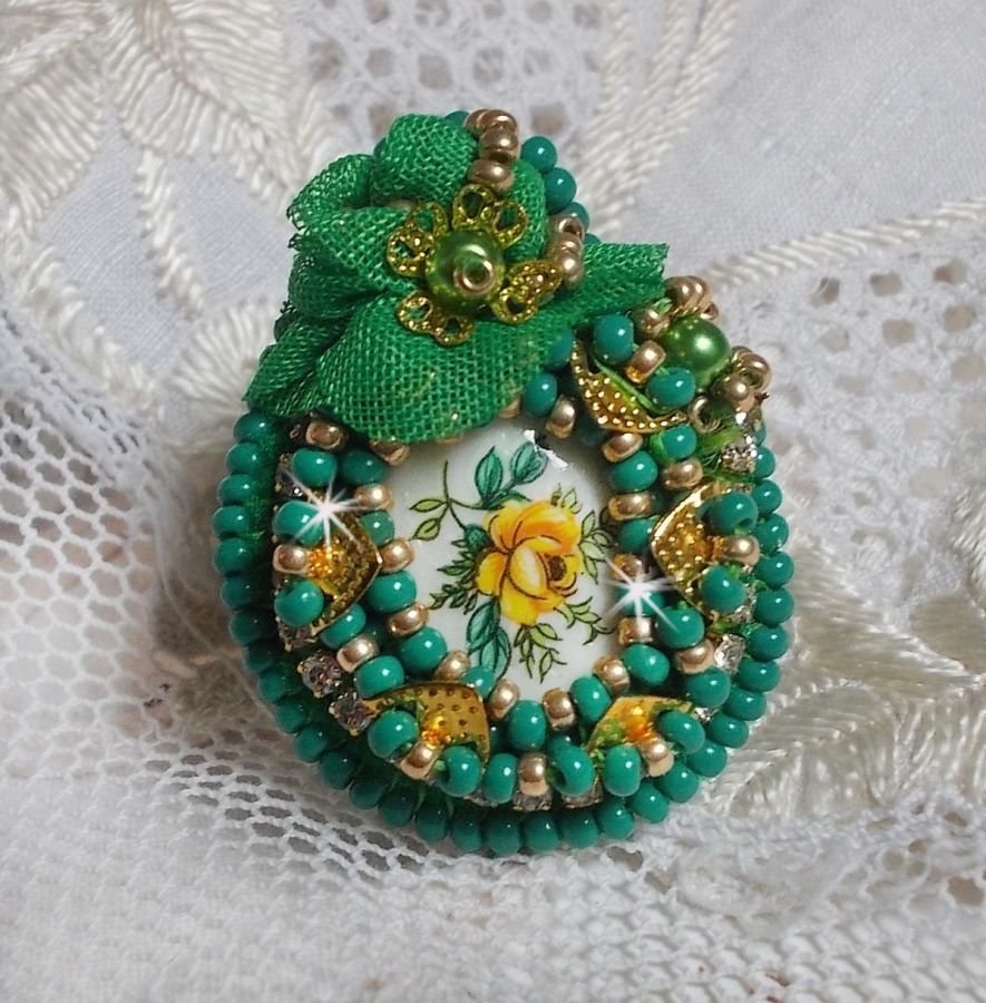 Vakker smaragdring med en keramisk cabochon laget av en gul og grønn rose