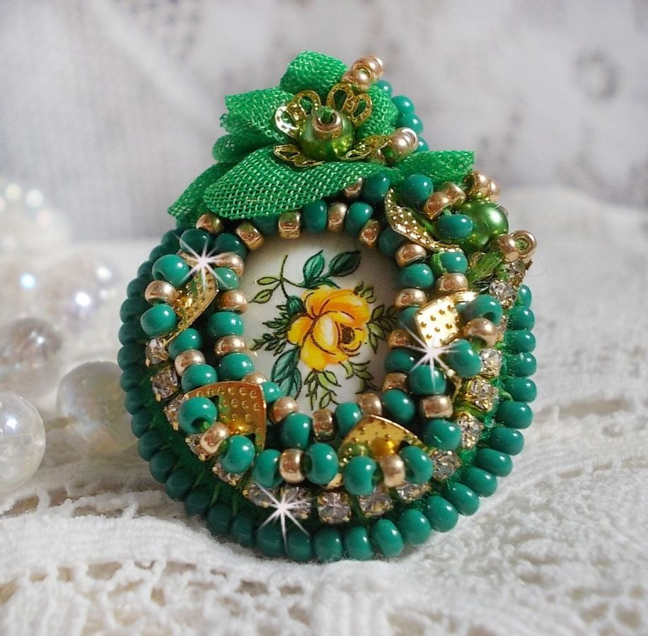 Vakker smaragdring med en keramisk cabochon laget av en gul og grønn rose