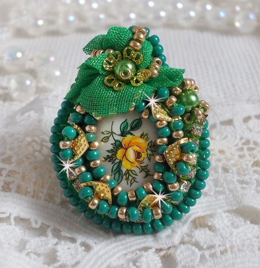 Vakker smaragdring med en keramisk cabochon laget av en gul og grønn rose