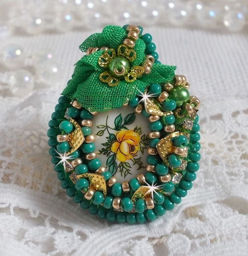Vakker smaragdring med en keramisk cabochon laget av en gul og grønn rose