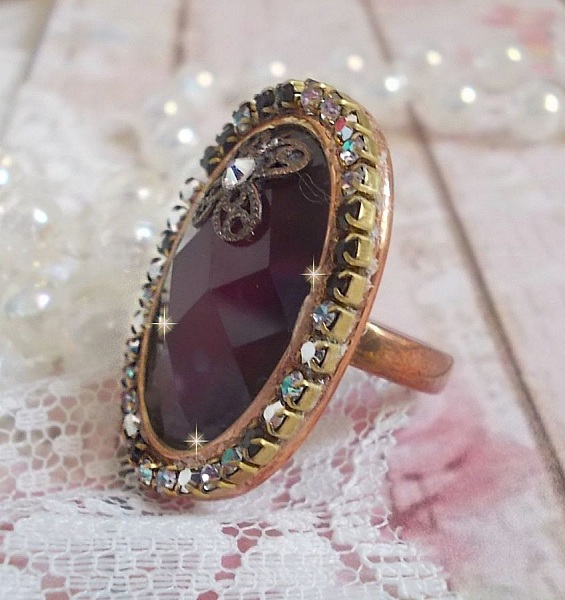 Elegant Burgundy-ring laget med PureCrystal-krystaller, et blomsterformet stempel og en glass cabochon.