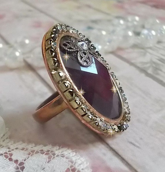 Elegant Burgundy-ring laget med PureCrystal-krystaller, et blomsterformet stempel og en glass cabochon.
