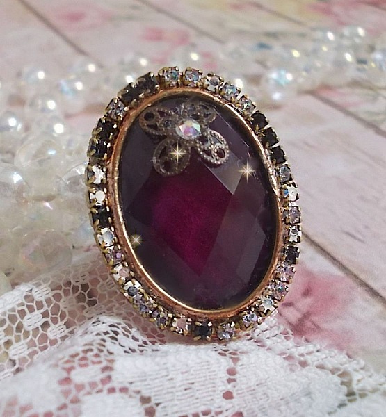 Elegant Burgundy-ring laget med PureCrystal-krystaller, et blomsterformet stempel og en glass cabochon.