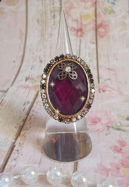 Elegant Burgundy-ring laget med PureCrystal-krystaller, et blomsterformet stempel og en glass cabochon.