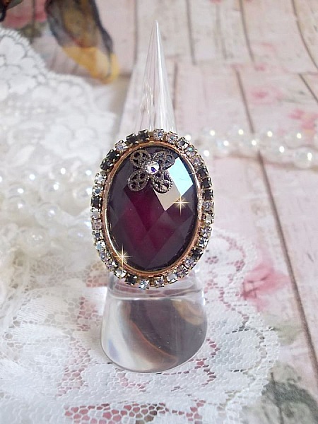 Elegant Burgundy-ring laget med PureCrystal-krystaller, et blomsterformet stempel og en glass cabochon.