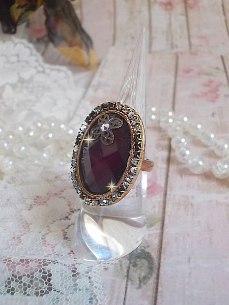 Elegant Burgundy-ring laget med PureCrystal-krystaller, et blomsterformet stempel og en glass cabochon.