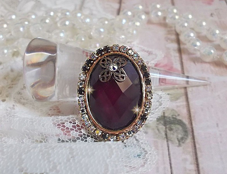 Elegant Burgundy-ring laget med PureCrystal-krystaller, et blomsterformet stempel og en glass cabochon.