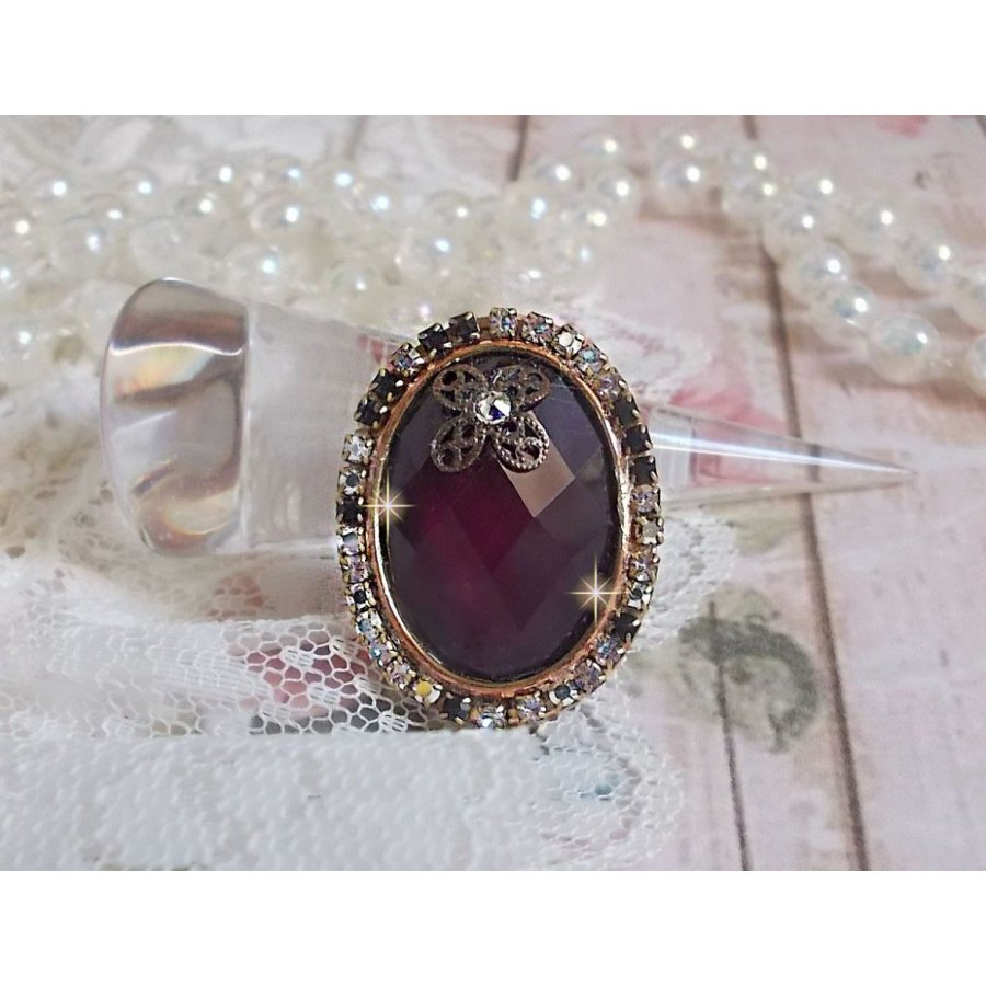 Elegant Burgundy-ring laget med PureCrystal-krystaller, et blomsterformet stempel og en glass cabochon.