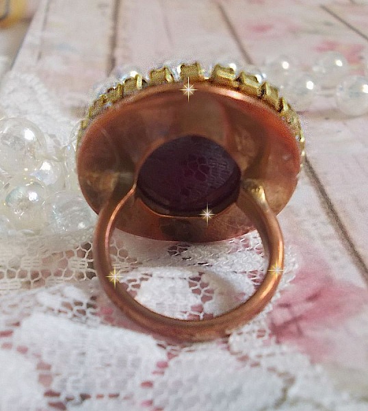 Elegant Burgundy-ring laget med PureCrystal-krystaller, et blomsterformet stempel og en glass cabochon.