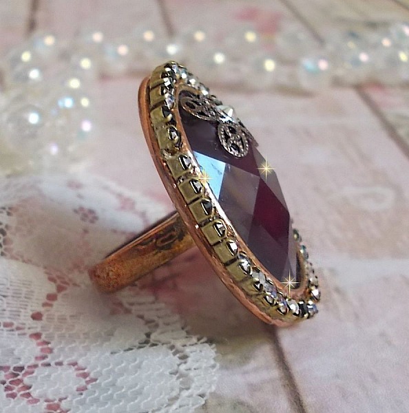 Elegant Burgundy-ring laget med PureCrystal-krystaller, et blomsterformet stempel og en glass cabochon.