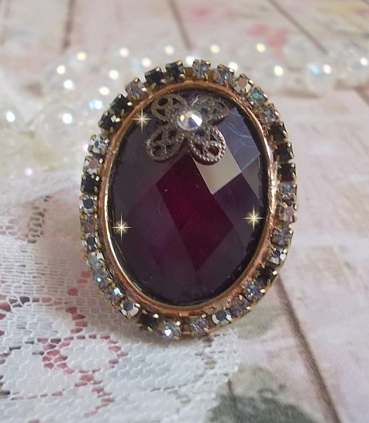 Elegant Burgundy-ring laget med PureCrystal-krystaller, et blomsterformet stempel og en glass cabochon.