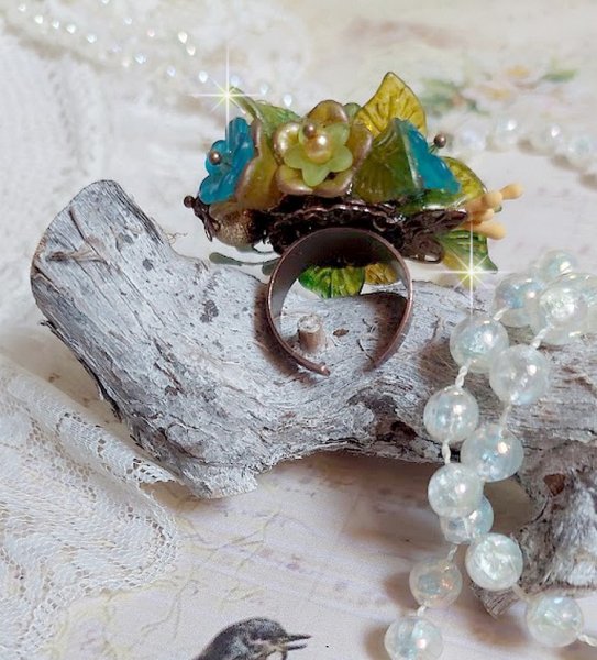 Bague C&eacute;zanne mont&eacute;e avec des petites fleurs lucites peintes &agrave; la main &agrave; laquelle s&rsquo;ajoute des feuilles, cristaux, perles, &eacute;tamines, grosses rocailles, perles nacr&eacute;es et m&eacute;tal sur une bague en Laiton