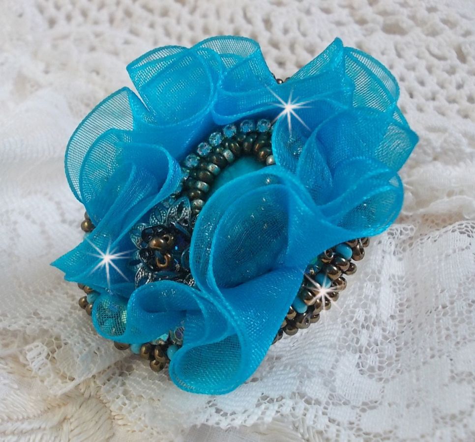 Ilycia sjarmerende ring brodert med en fasettert turkisblå harpiks cabochon og et organzabånd