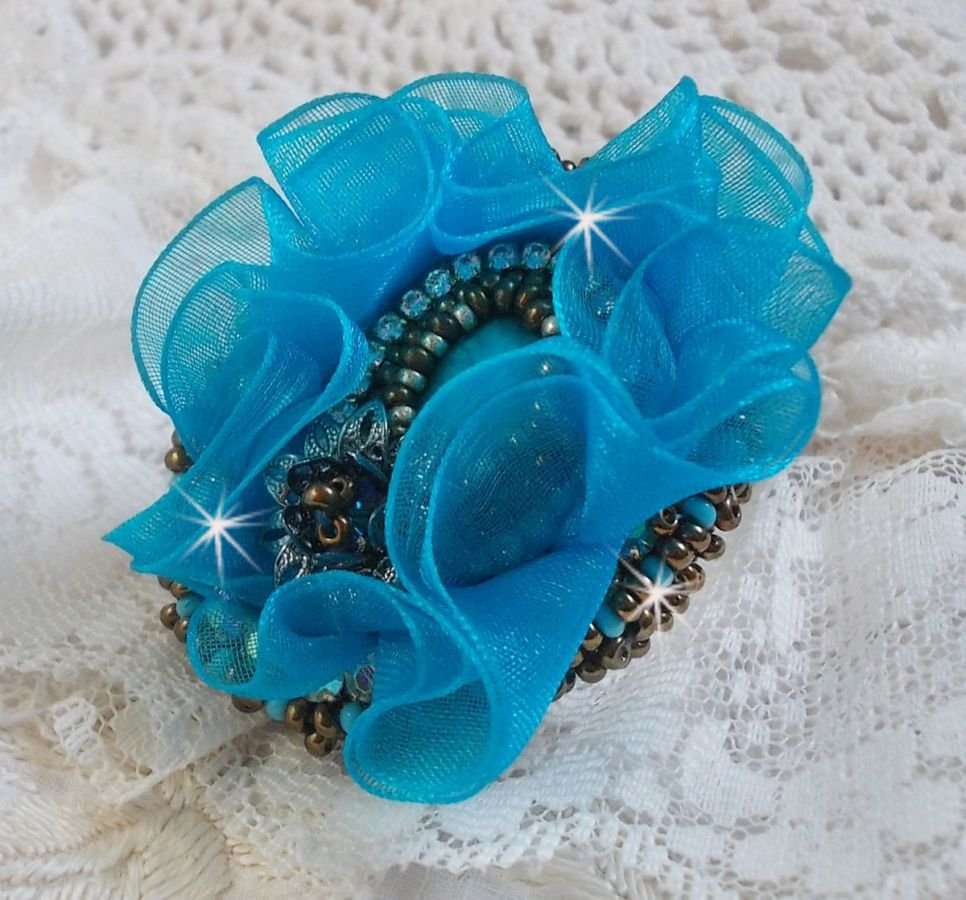 Ilycia sjarmerende ring brodert med en fasettert turkisblå harpiks cabochon og et organzabånd