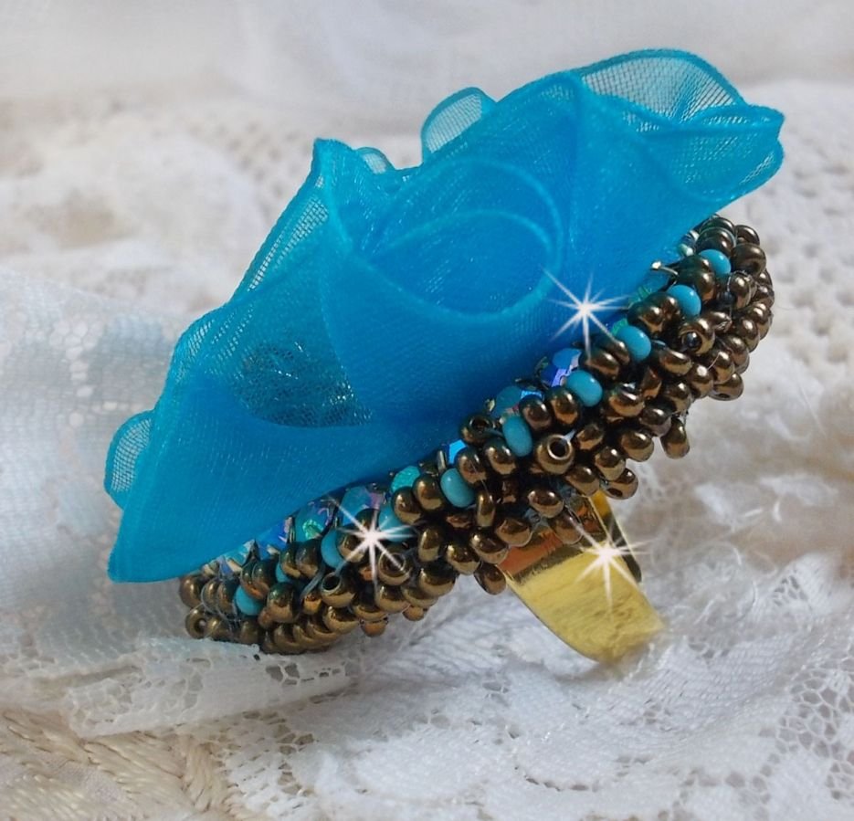 Ilycia sjarmerende ring brodert med en fasettert turkisblå harpiks cabochon og et organzabånd