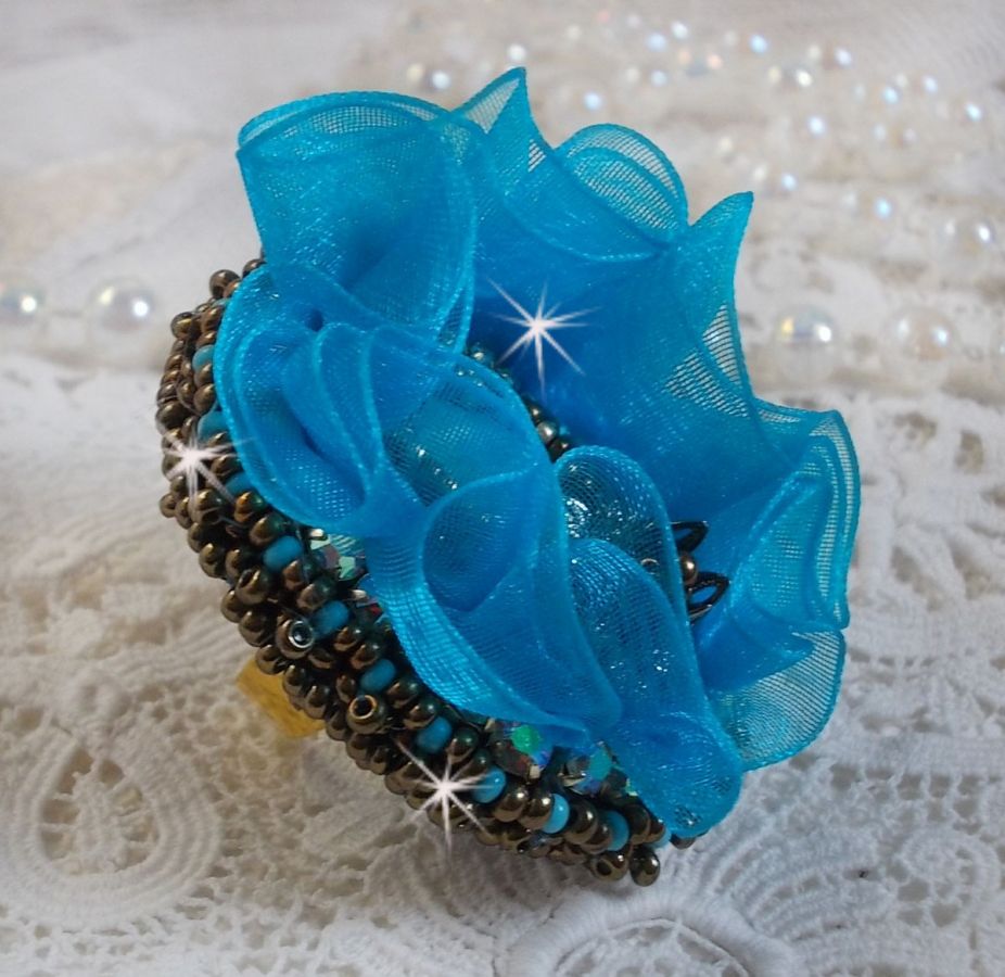 Ilycia sjarmerende ring brodert med en fasettert turkisblå harpiks cabochon og et organzabånd