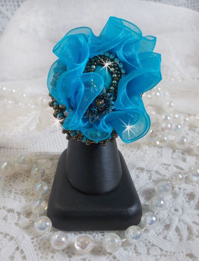 Ilycia sjarmerende ring brodert med en fasettert turkisblå harpiks cabochon og et organzabånd