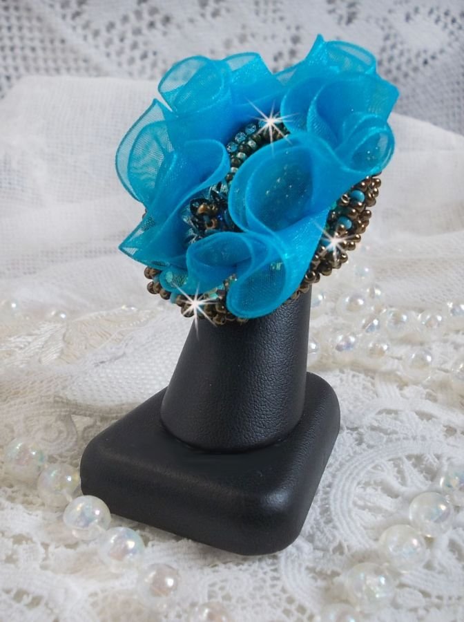 Ilycia sjarmerende ring brodert med en fasettert turkisblå harpiks cabochon og et organzabånd