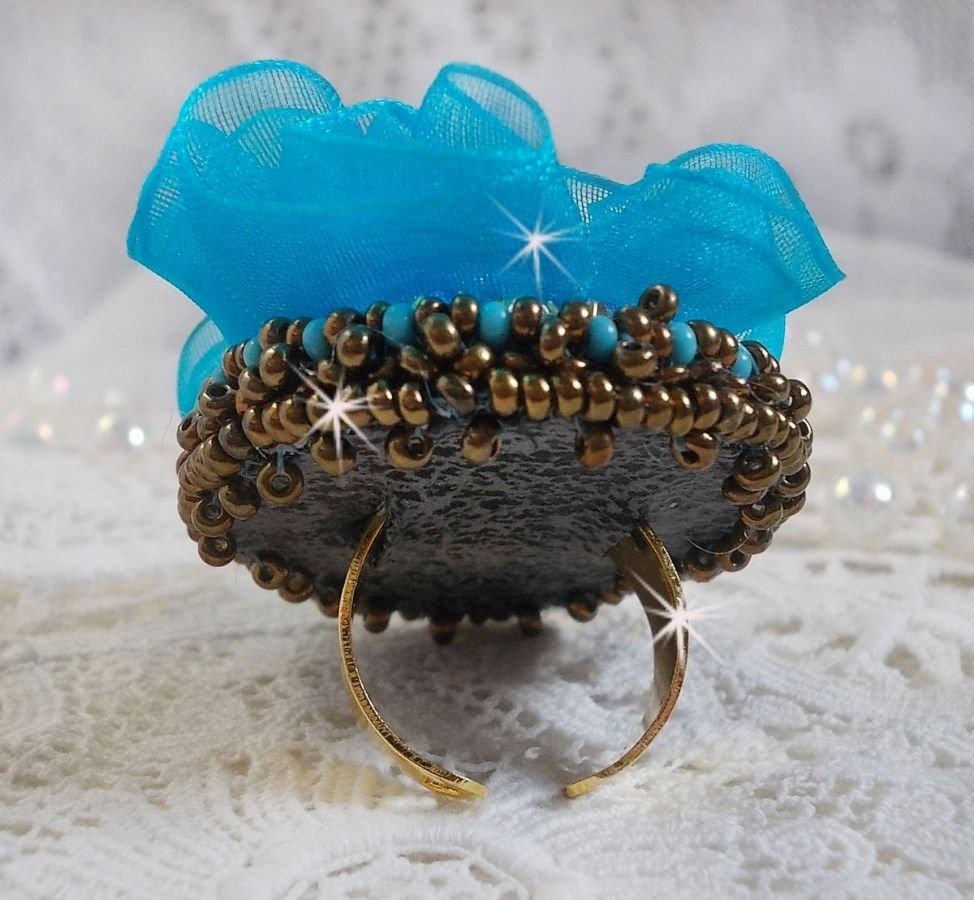 Ilycia sjarmerende ring brodert med en fasettert turkisblå harpiks cabochon og et organzabånd