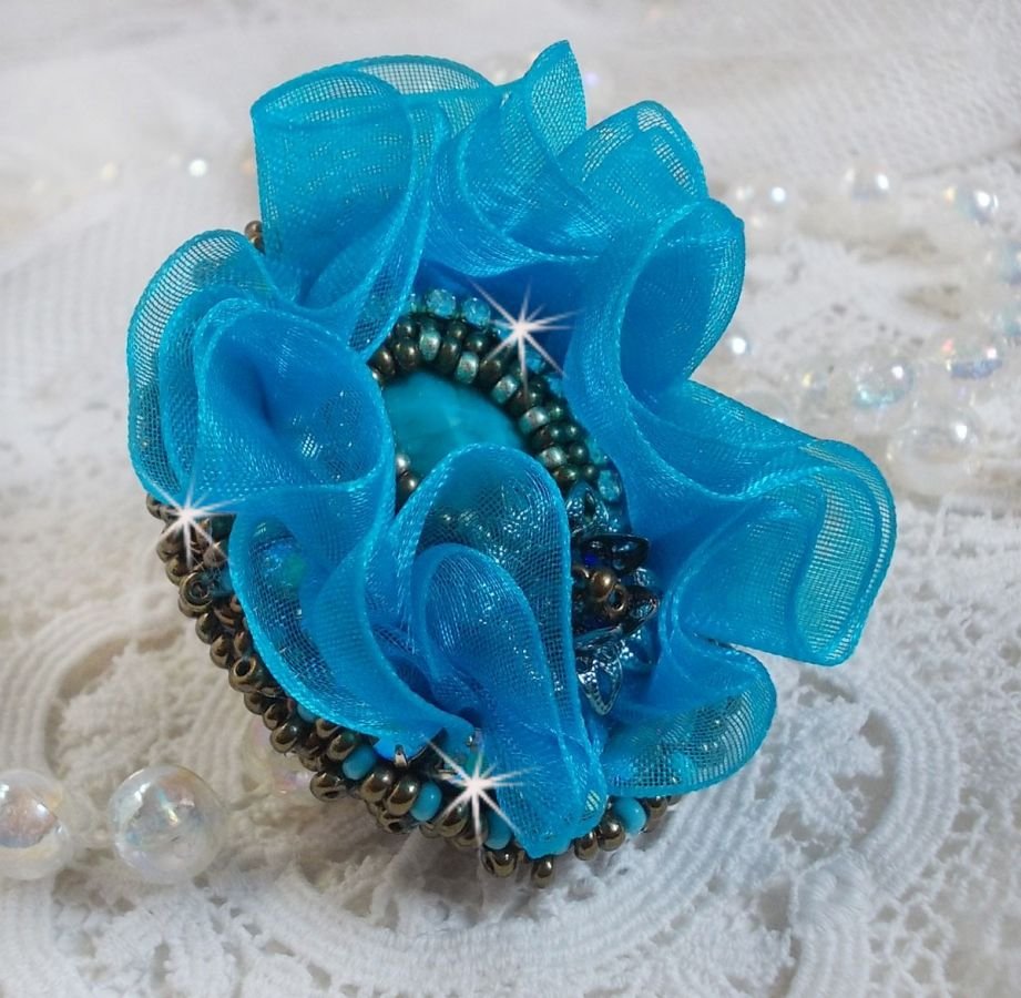 Ilycia sjarmerende ring brodert med en fasettert turkisblå harpiks cabochon og et organzabånd