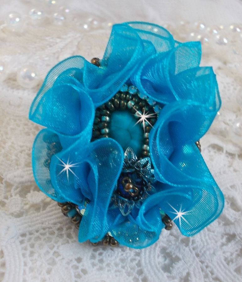 Ilycia sjarmerende ring brodert med en fasettert turkisblå harpiks cabochon og et organzabånd