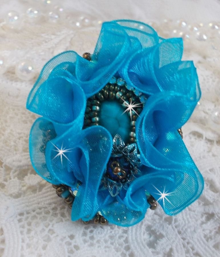 Ilycia sjarmerende ring brodert med en fasettert turkisblå harpiks cabochon og et organzabånd