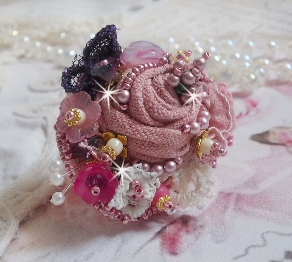 Poetisk hagering brodert med lin, fine blonder, Swarovski-krystaller, perlemorblad, lucitablomster, glassperler og frøperler. 