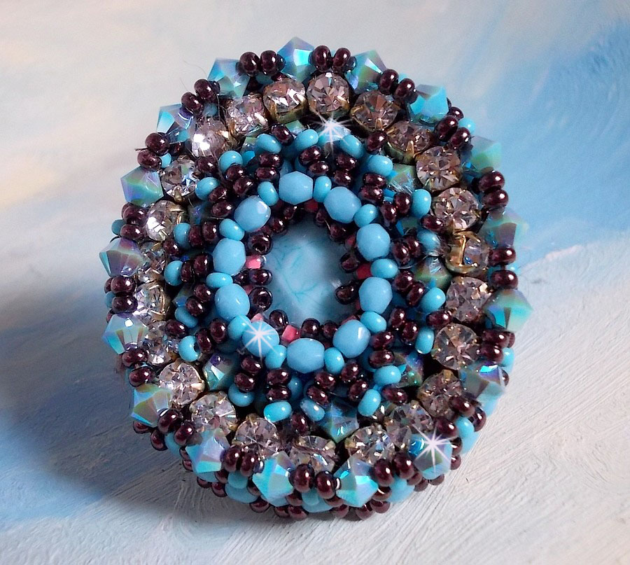 Naïade ring brodert med en turkisblå harpiks og krystall cabochon, et vakkert lysspill.