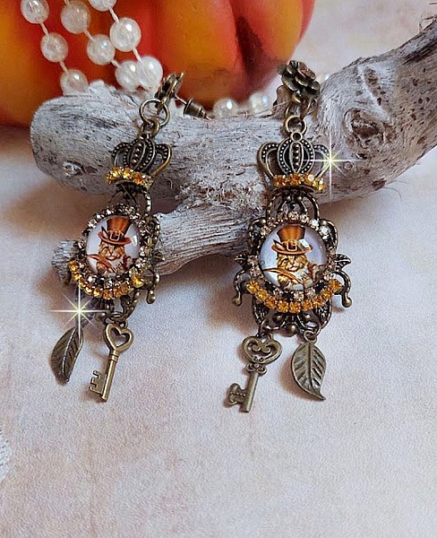 BO Chatibo Steampunk mont&eacute;es avec cabochons ronds en verre repr&eacute;sentant un chat chapeaut&eacute; Haute de Forme Orange. Strass&eacute;es avec une couronne, breloques cl&eacute;s et feuilles. Mont&eacute;es sur clips Bronze