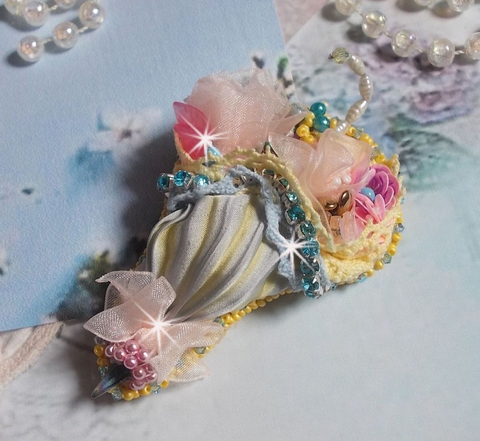 Blomsterparaplybrosje brodert med grå/gult silkebånd, Swarovski-krystaller, Lucite-blomster, perlemorperler, blonder og frøperler.