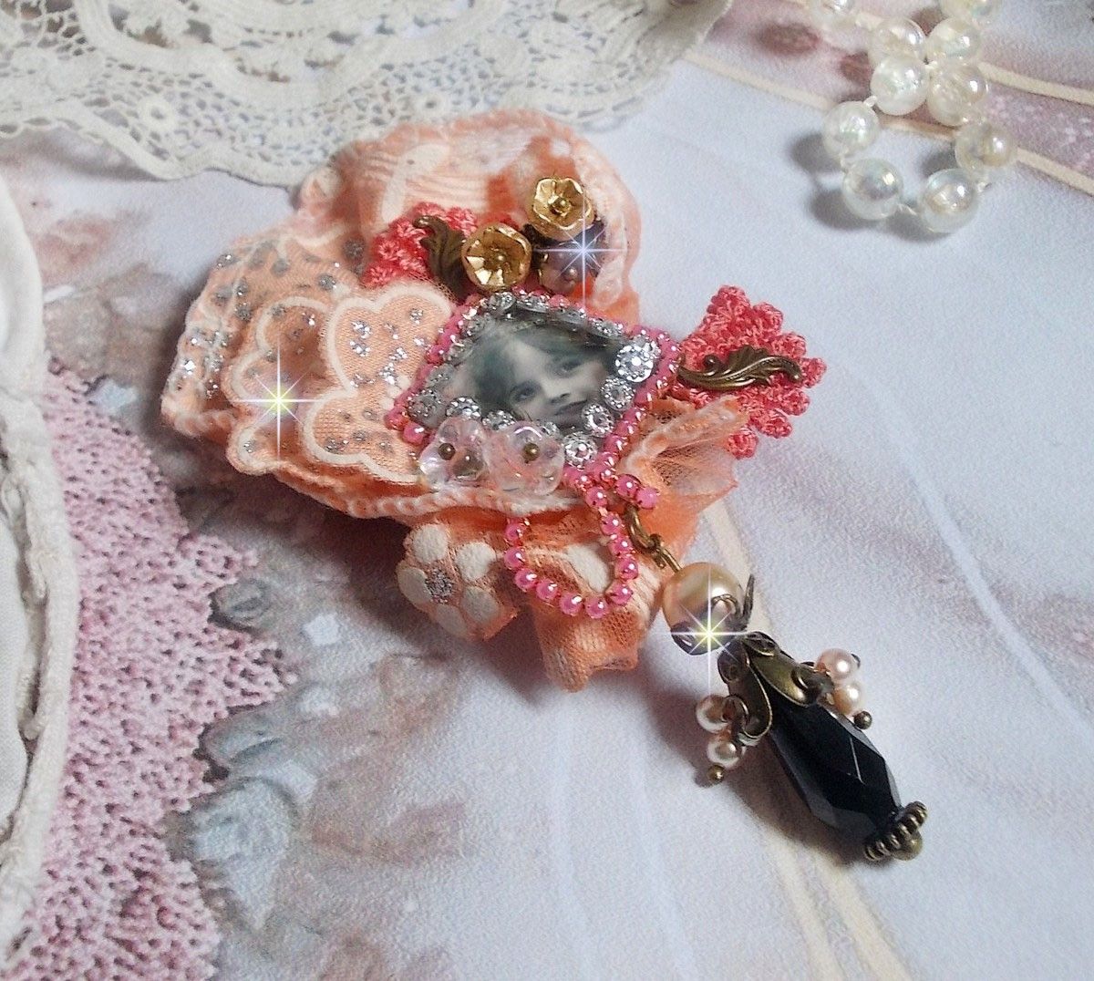 Rustikk Rose brosje laget med en cabochon som representerer en smilende jente, oransje rhinestone og Rose blonder, krystaller, glassperler og diverse tilbehør