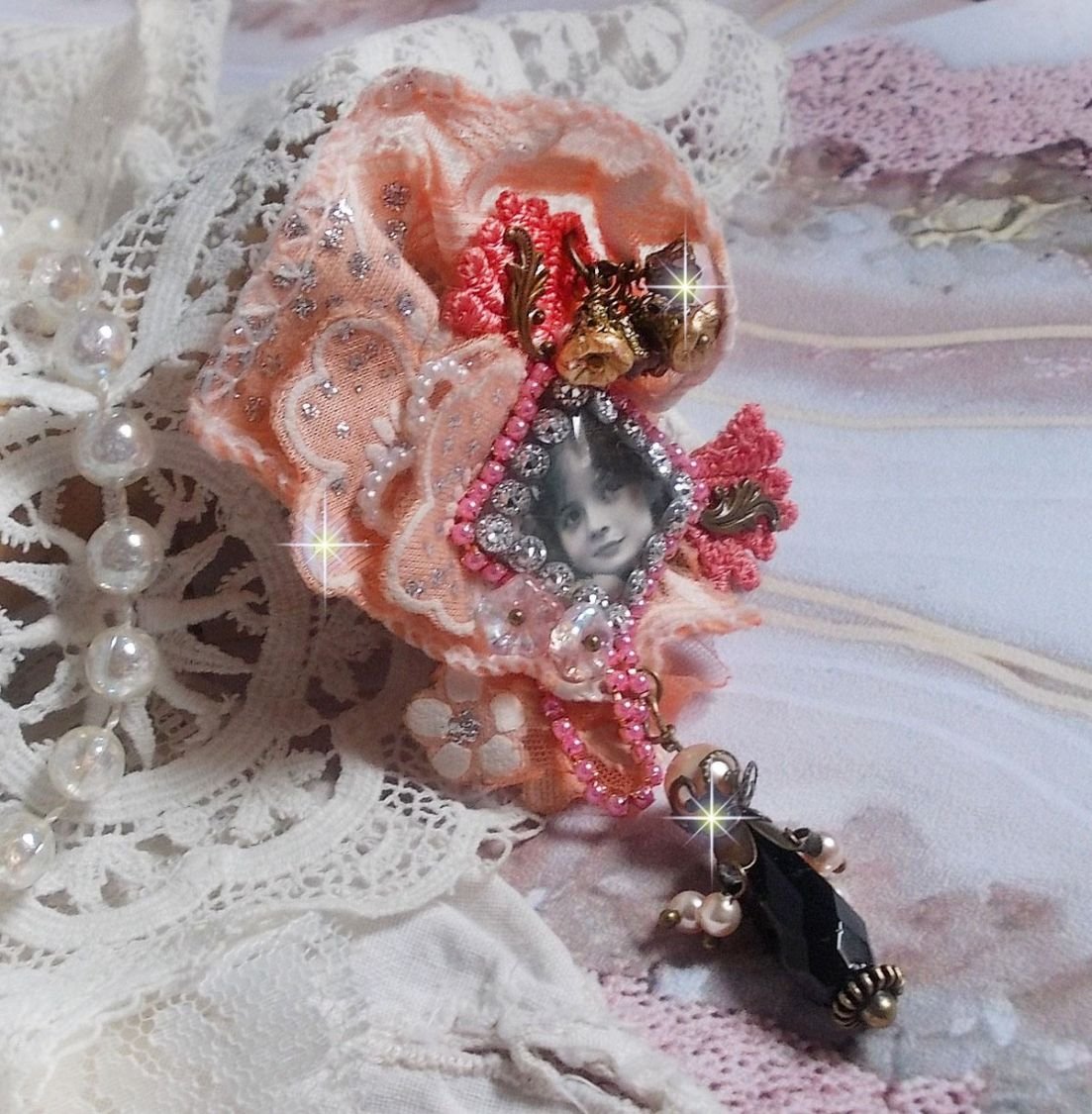 Rustikk Rose brosje laget med en cabochon som representerer en smilende jente, oransje rhinestone og Rose blonder, krystaller, glassperler og diverse tilbehør