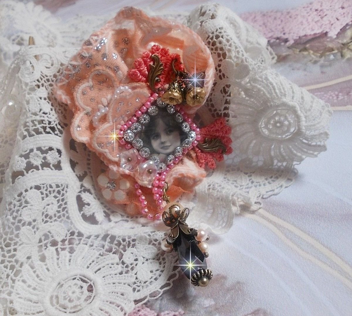 Rustikk Rose brosje laget med en cabochon som representerer en smilende jente, oransje rhinestone og Rose blonder, krystaller, glassperler og diverse tilbehør