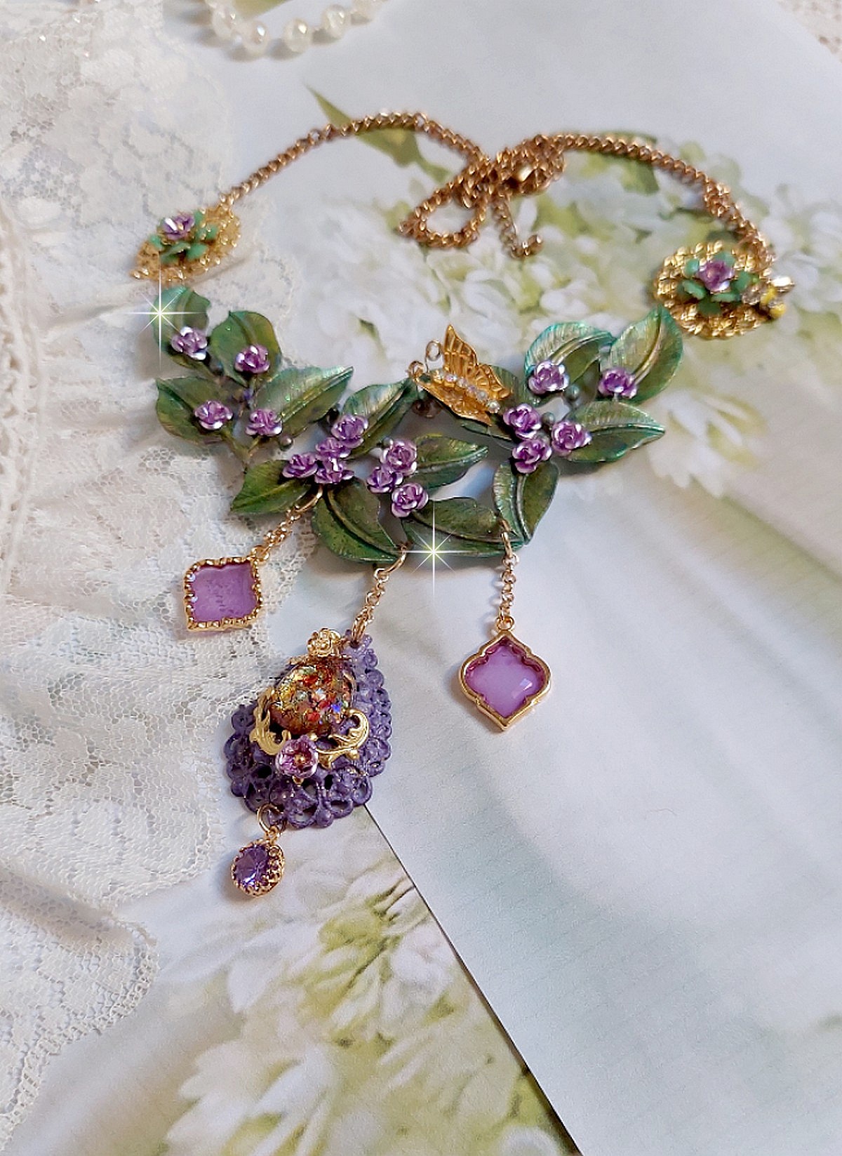 Collier Cam&eacute;lia Japonica mont&eacute; avec un motif feuilles aquarell&eacute;s &agrave; la main, paillettes, breloques papillons et abeille, roses m&eacute;tal, cabochon cristal, pendentifs &eacute;poxy aux couleurs d&rsquo;arc en ciel