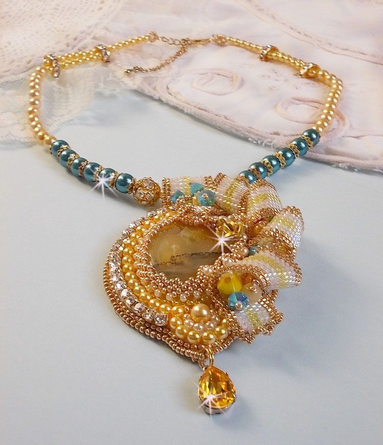 Haute-Couture Sunflower Gold anheng brodert med 24 karat gullbelagte frøperler, en Madagaskar opal og Swarovski krystaller.