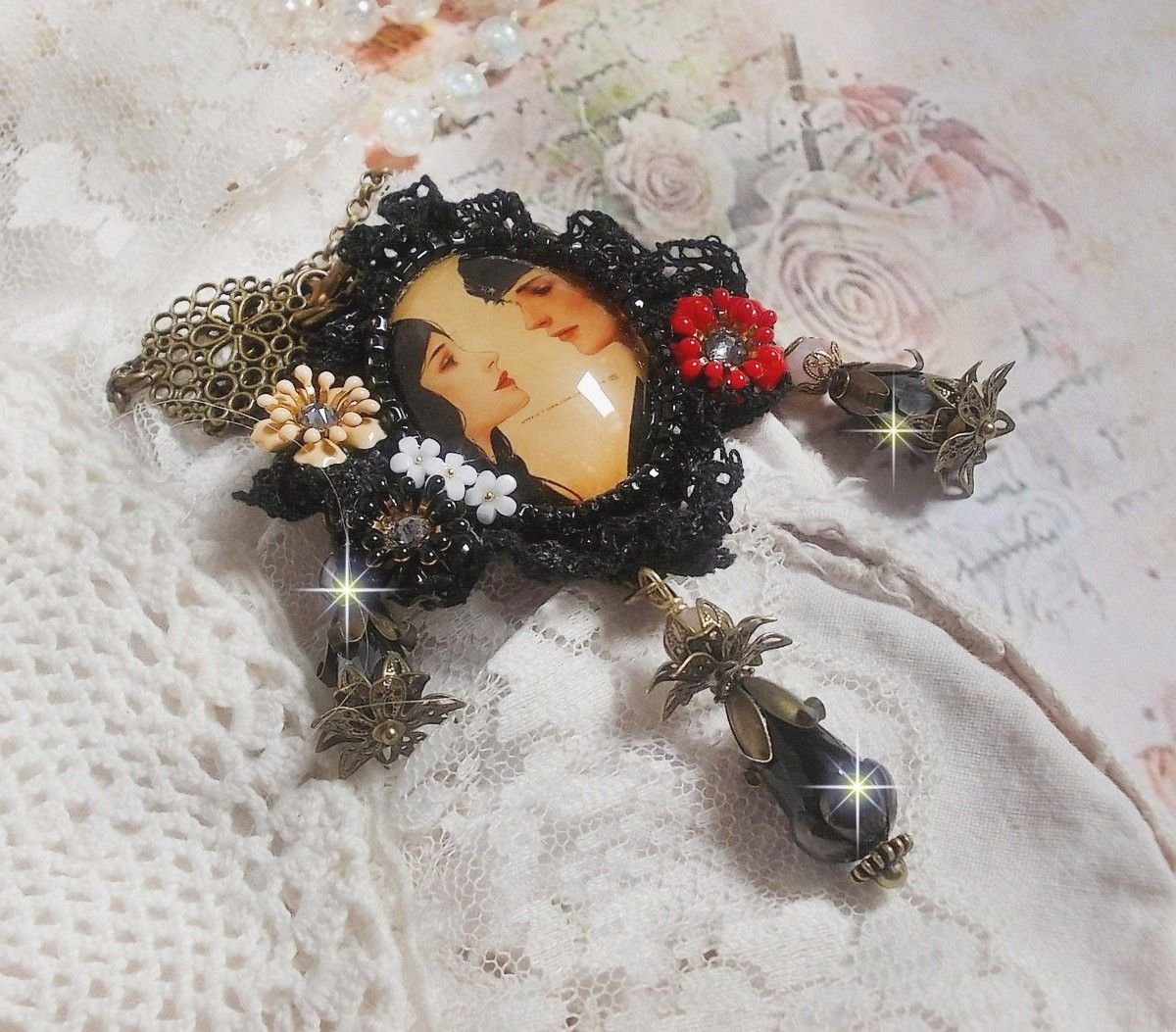 Love Romance halskjede laget med krystaller, en oval cabochon som representerer to kvinner, kvarts, hematitter, gullbelagte perler og annet tilbehør