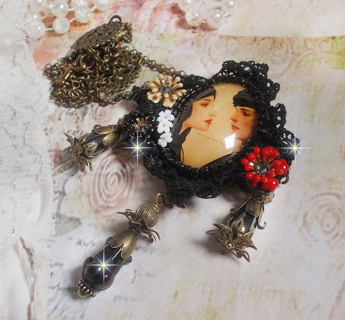 Love Romance halskjede laget med krystaller, en oval cabochon som representerer to kvinner, kvarts, hematitter, gullbelagte perler og annet tilbehør