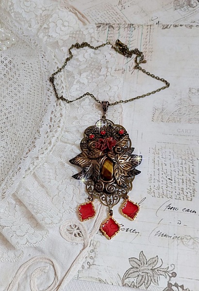 Pendentif M&eacute;lodie avec un cabochon &OElig;il de tigre orn&eacute; de perles en Jade Rouge vein&eacute; de Noir sur fleurs 5 p&eacute;tales et estampes mont&eacute;s sur une cha&icirc;ne bronze. Les pendants sont en r&eacute;sine &eacute;poxy Rouge