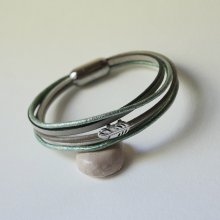 Armbånd i flere skinnfarger i beige, lysegrønne og perlemorfargede nyanser, dekorert med en liten fjær